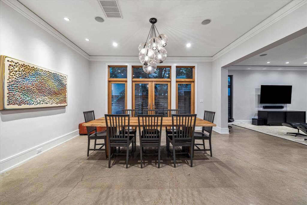 Viewed from the kitchen, the dining room becomes a usable space for everyday living off the living room.  Note the dramatic contemporary chandelier and additional ceiling speakers/audio zone.  The bar is located between the dining room and kitchen and features a SubZero refrigerator, sink and lighted cabinets.