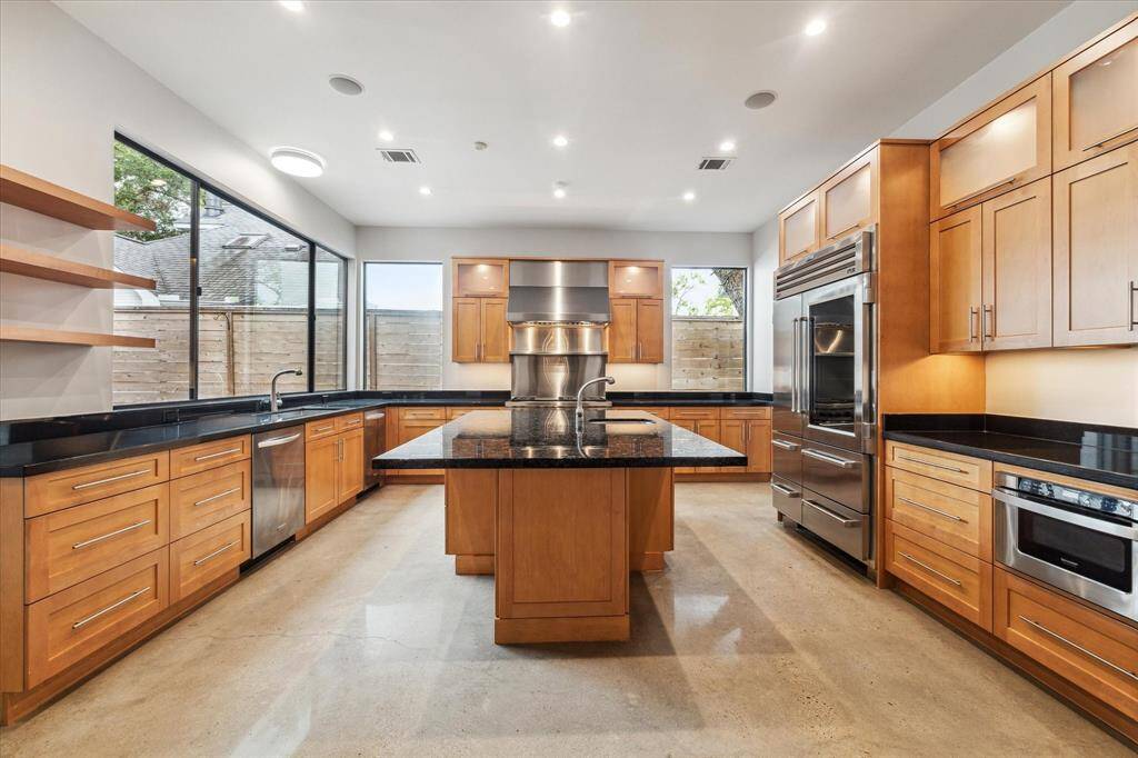 This kitchen offers contemporary elegance, with picture windows, custom cabinetry and expansive black stone counters yet all the requirements for the entertaining chef, with top of the line appliances and 2 Kitchenaid dishwashers flanking the sink overlooking the decked patio.  Note the built-in breakfast bar seating around the island storage cabinets.  The Sharp drawyer microwave on the right is out of the chef's triangle near the entry to the pantry.  Every detail has been thoughtfully designed.