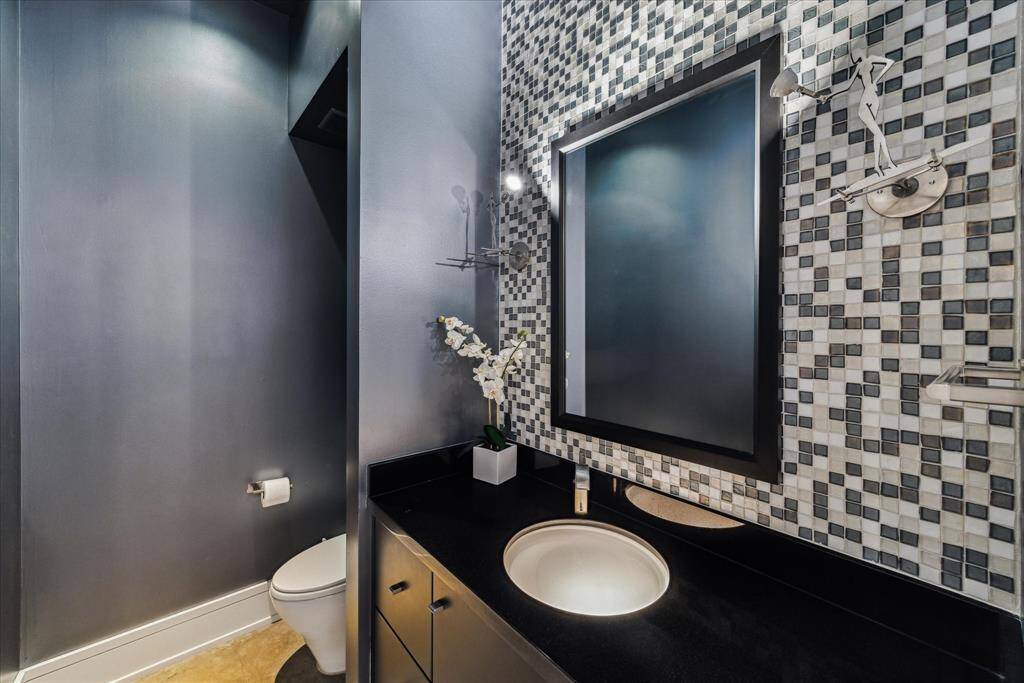 The guest bath, well-located away from the living space and next to the study, is a timeless contemporary design with tile accent wall and glass basin lit from underneath.