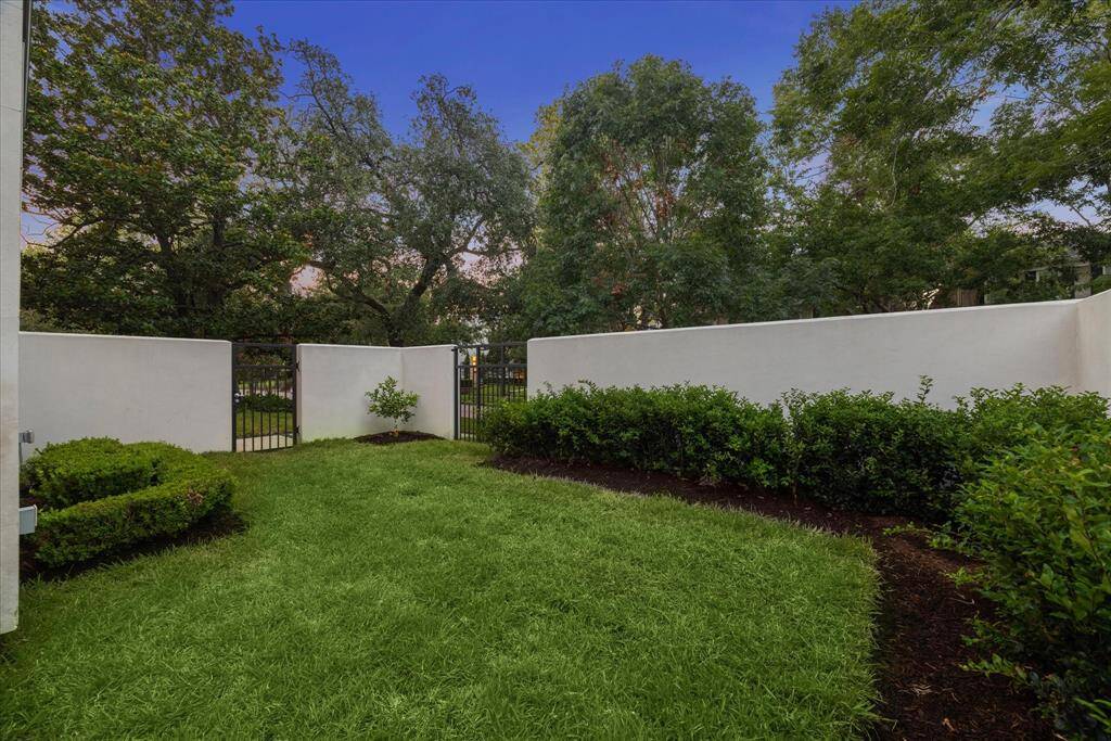 The walled yard is a secured spot for the kids to play and the iron segments offer a spot to chat with neighbors and add interest to the view.  The smaller iron segment is a gate to the front walk.  Recently re-sodded and re-landscaped, the corner features a citrus tree and the shrubs and turf are untrimmed, as they are rooting.