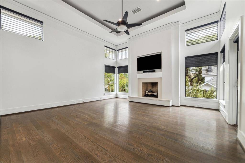 The primary suite is truly spectacular, with 12' high, coffered ceiling, a double row of windows (10 total!), elegant blinds and open, gas log fireplace.  Measuring 17'x 17' this bright, spacious room is a sanctuary with views and a door to the 2nd floor balcony.  The second level windows are electric, remote control blackout blinds.  The mounted TV and soundbar recessed above the fireplace remains for the Buyer.