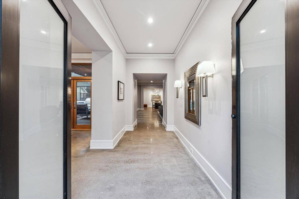 Welcome guests through the contemporary, commercial-grade, steel double swing entry doors. The entry is over 17' long and has two discrete, push latch coat closets on the way to the living room. The sitting room to the left provides an elegant entertaining space with great views of the front yard.