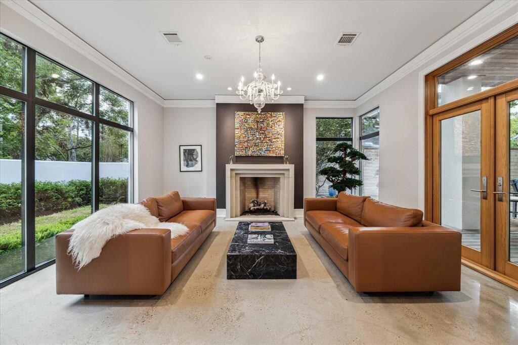 The beautiful sitting room doubles as an atrium to enjoy the walled yard and loggia/deck views, with three walls of windows. The wood doors to the right lead to the common outdoor space, expanding the space for entertaining.