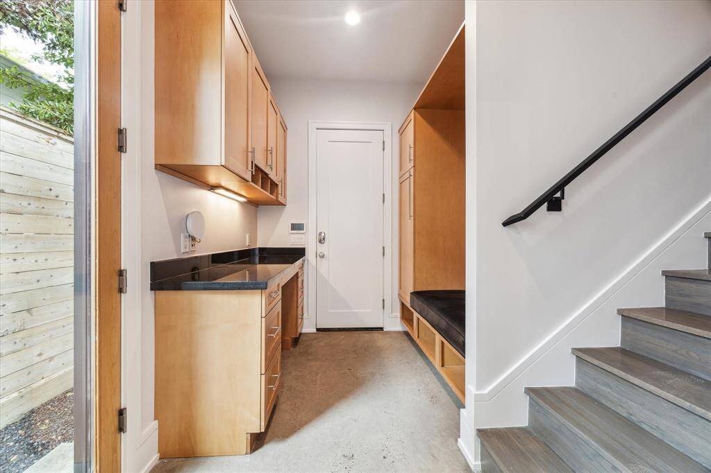 The mud room offers storage and shoe hutches directly off the garage, at the base of the secondary stairs.  Note the custom-wired wifi extender in the picture and the convenient third alarm keypad at the entry.