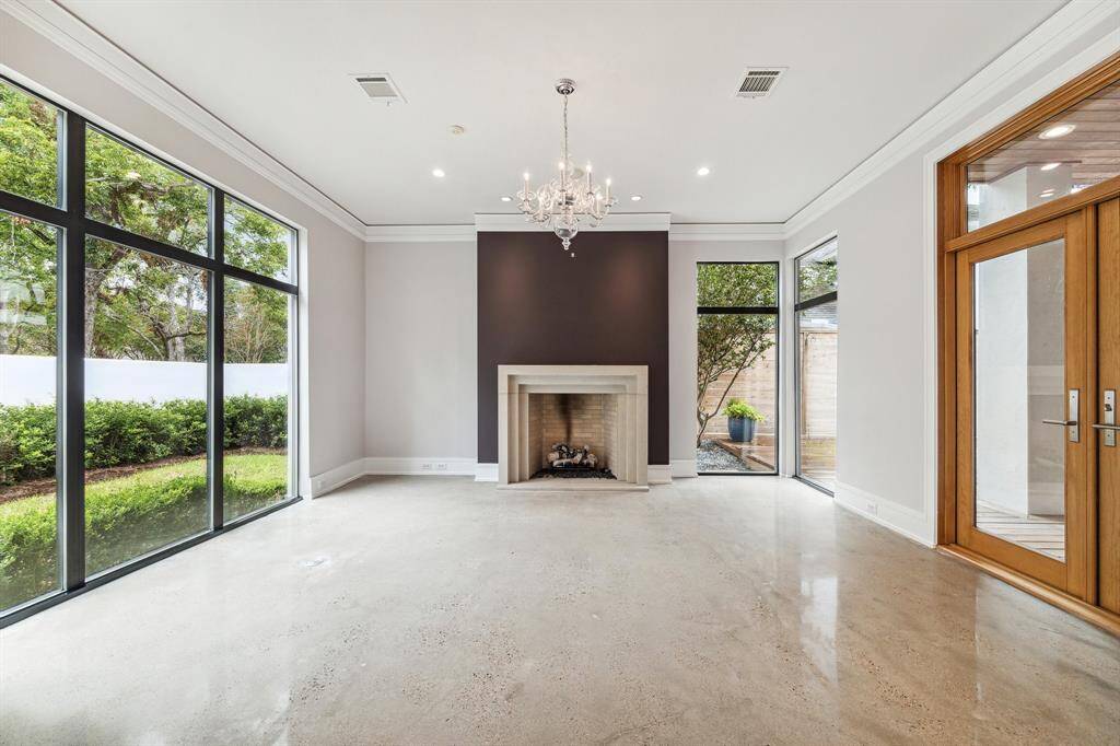 Note the recently-refinished, low maintenance, modern concrete floors and dramatic geometric stone fireplace mantle. Flooring can be easily overlayed by new owner, if desired.