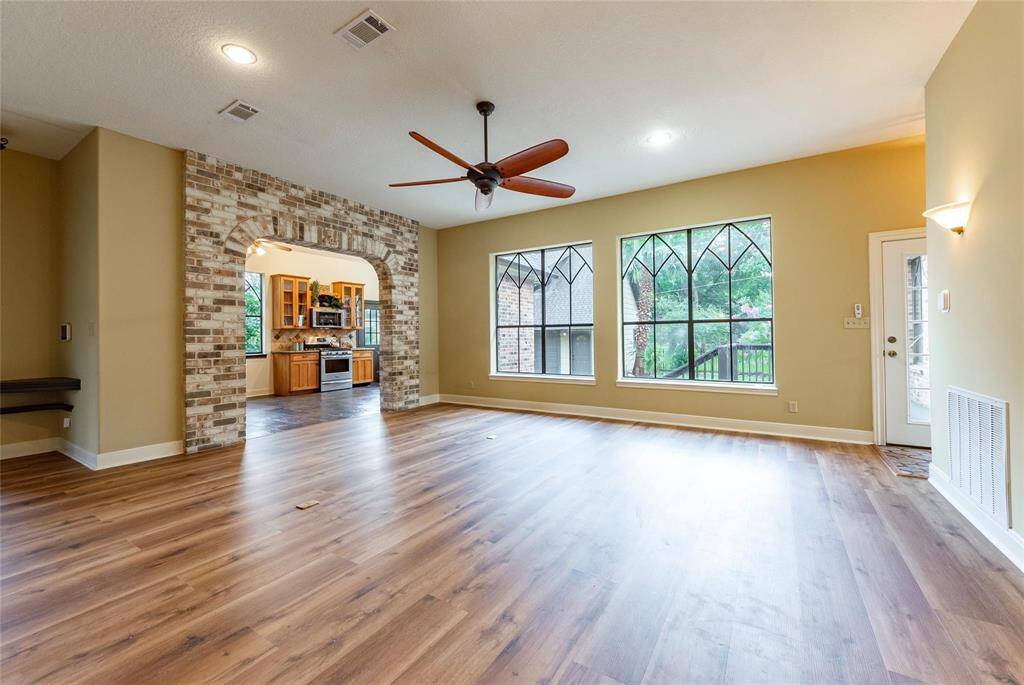 Spacious family room with new luxury vinyl plank flooring, stone accent walls, sconce lighting, upscale ceiling fan and custom designed windows.