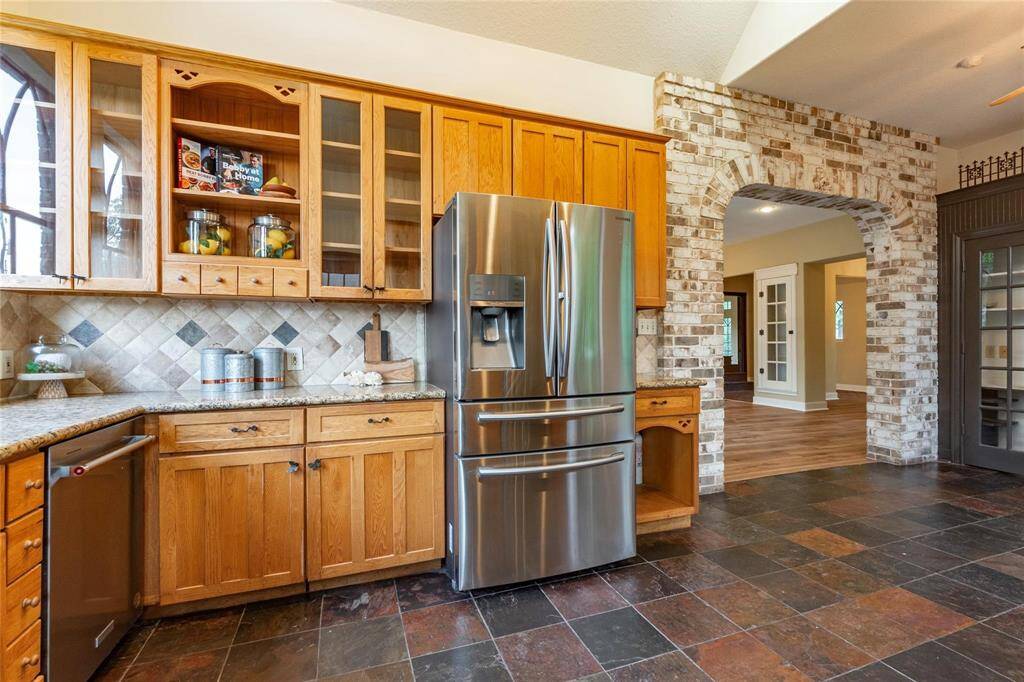 Amble kitchen storage space with glass-front cabinets and stainless-steel side-by-side refrigerator.