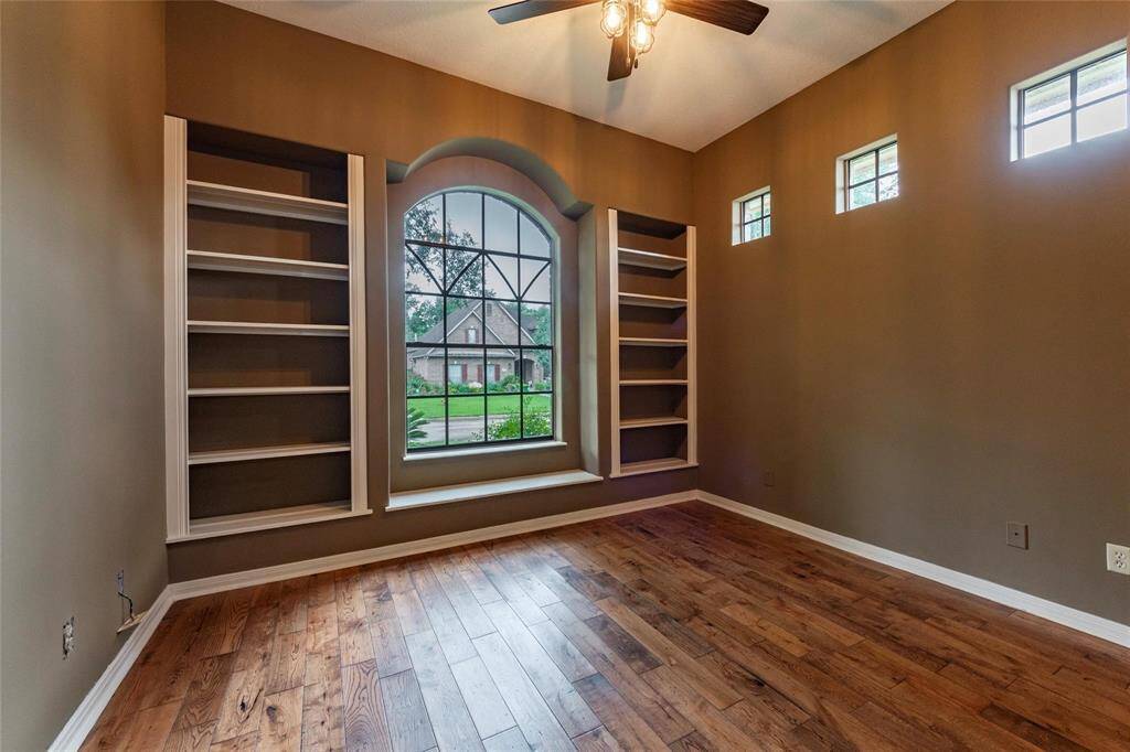 Spacious secondary bedroom on the first floor with high ceilings, luxury vinyl plank flooring and custom built-in storage shelves.