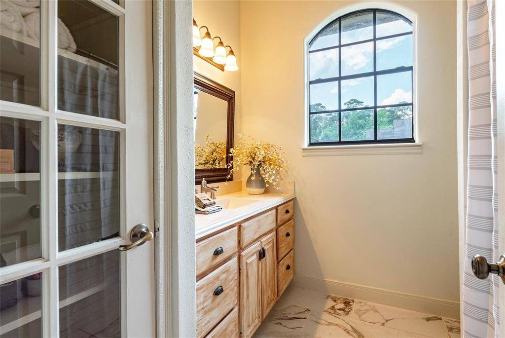 Lovely full bathroom downstairs with updated tile flooring, French door linen closet, framed mirror and tub/shower combination.