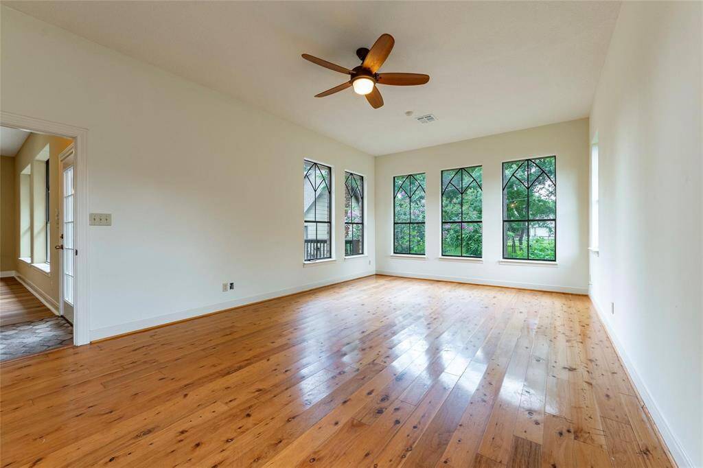Oversized, beautiful primary bedroom with wood floors, high ceilings and attractive large windows with backyard views.