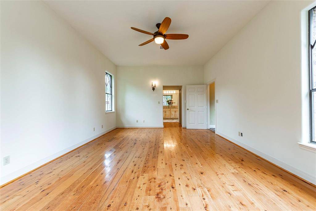Another view of the large primary bedroom with upscale ceiling fan and sconce lighting.