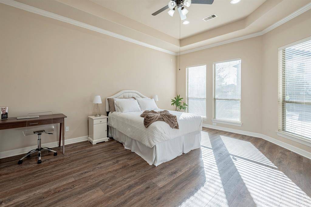 This luxurious Primary suite features, Trey ceilings, Crown molding, walls of windows, and wood flooring.