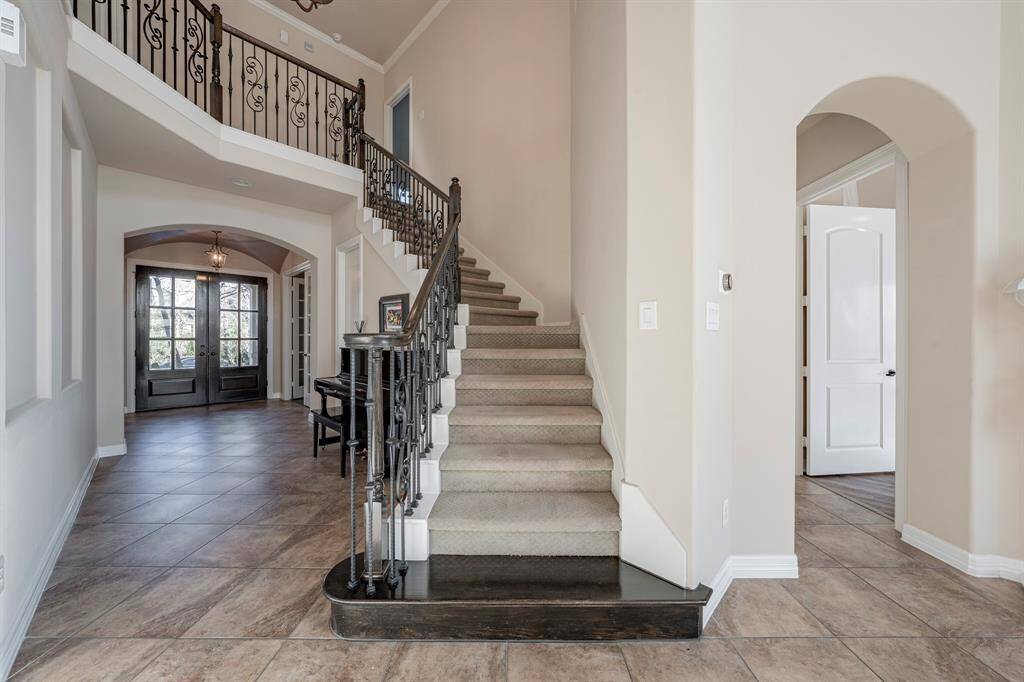An elegant curved staircase has iron railings and hardwood landing