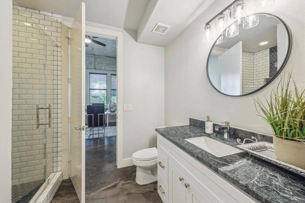The ensuite bathroom features a large shower with subway wall tiles and hexagon floor tiles, marble countertops, a walk-in closet, and under sink storage.