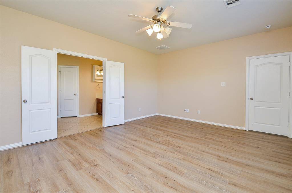 Discover the charm of this primary room featuring elegant French doors and stylish wood-look vinyl flooring.