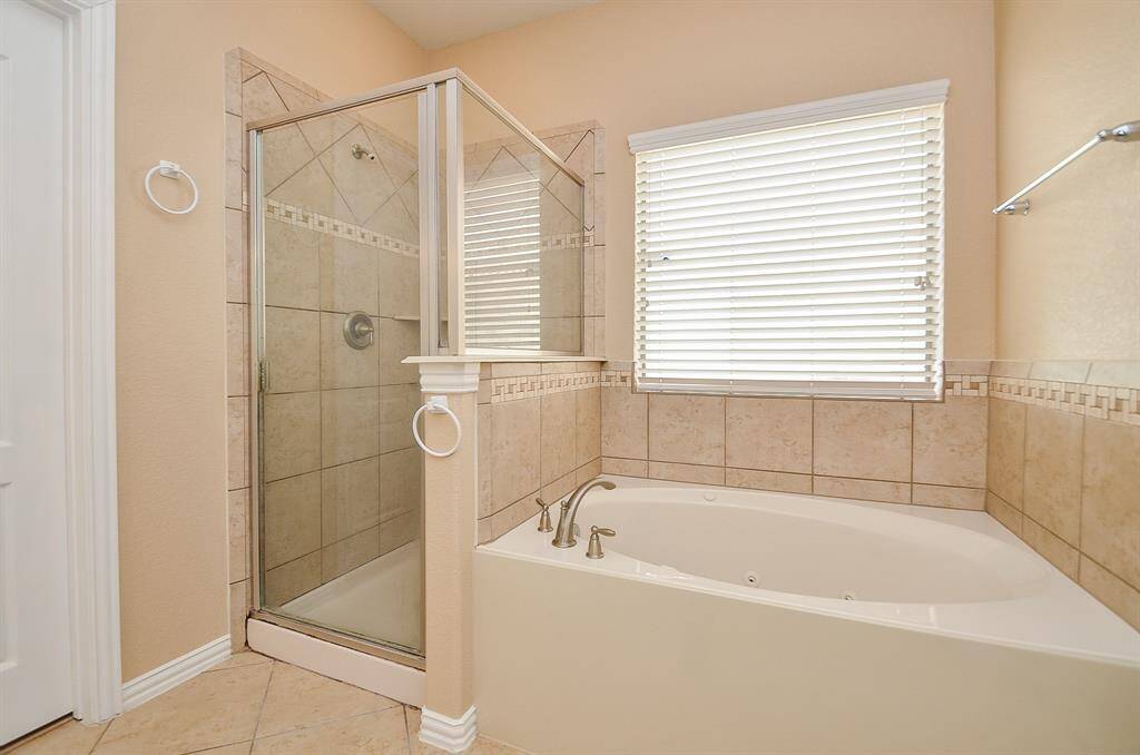 Experience luxury in the primary bathroom, featuring both a sleek shower and a relaxing bathtub.