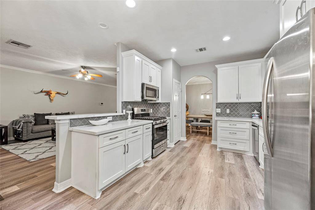 Crisp white cabinets with updated hardware provide a clean and timeless look, enhancing the sense of brightness and openness in the space.