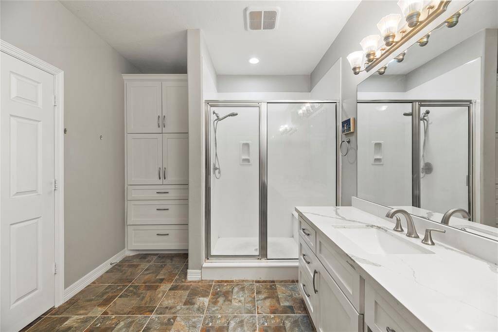 The expansive walk-in shower, with a sleek glass front, offers a luxurious escape for a quick rinse or a refreshing retreat.