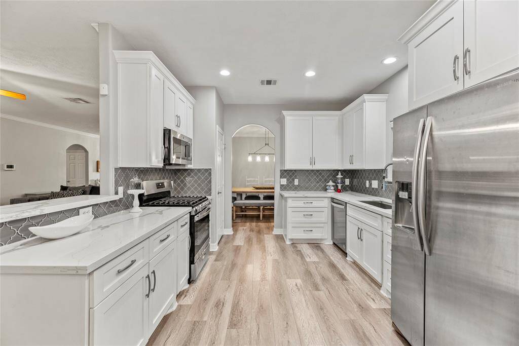Your chef inspired kitchen awaits! Features include granite countertops paired with a coordinating tiled backsplash, stainless steel appliances, crisp white cabinets with updated hardware, recessed lighting, and breakfast bar seating.