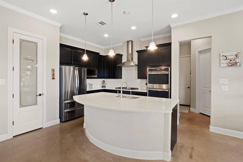 The kitchen boasts quartz countertops, a gas cooktop island, a breakfast bar, hex tile backsplash, pot and pan drawers, and a reverse osmosis system, making it a chef's dream.