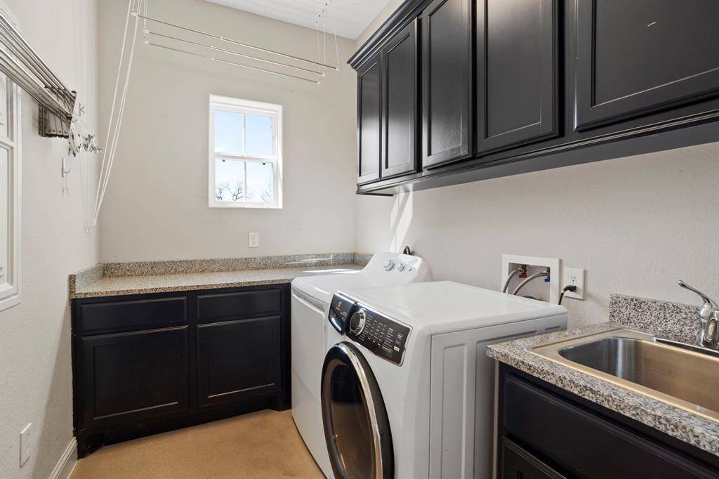 The in-home laundry room boasts a full-sized stainless steel sink, built-in storage cabinets, and sleek granite countertops, making it perfect for folding clothes or tackling projects.