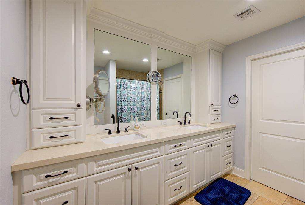 Primary bathroom with two sinks and additional storage space.