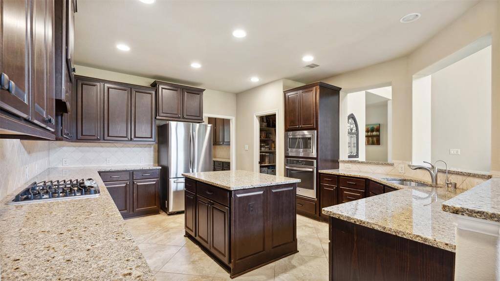 Gourmet kitchen with extended granite island bar, stainless steel appliances, a gas cooking range and easy to clean 14x14 inch tiled floors.