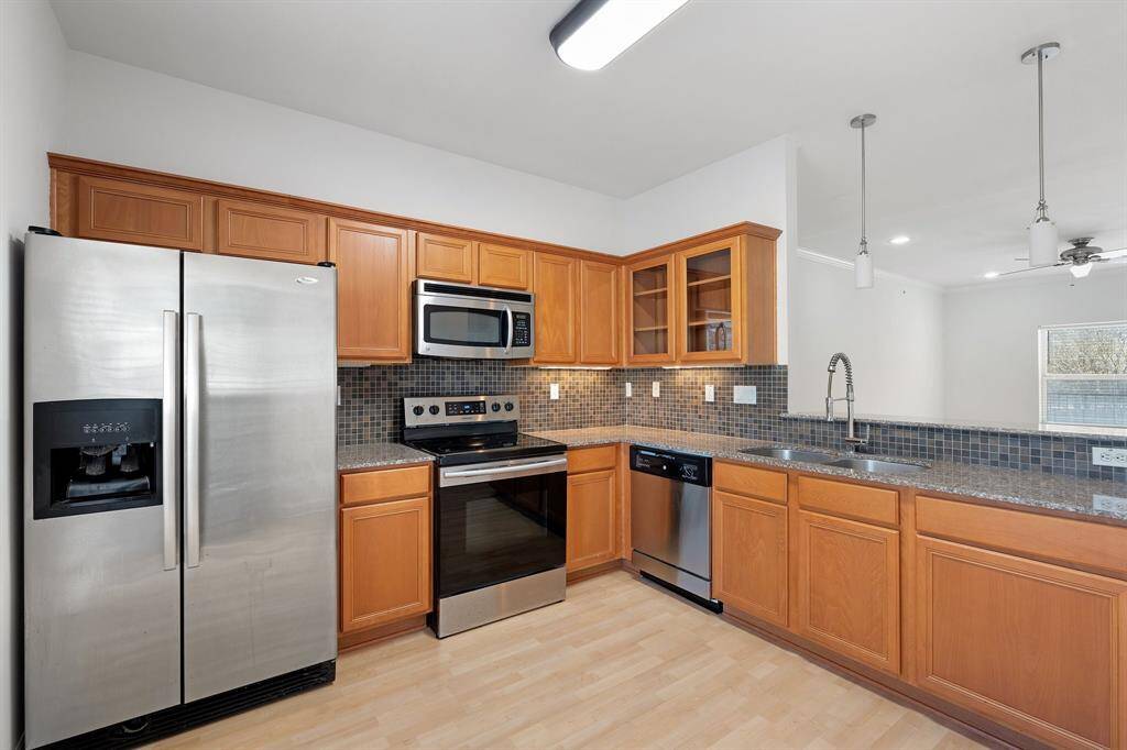 The kitchen features wood cabinets, tile backsplash, and stainless steel appliances.