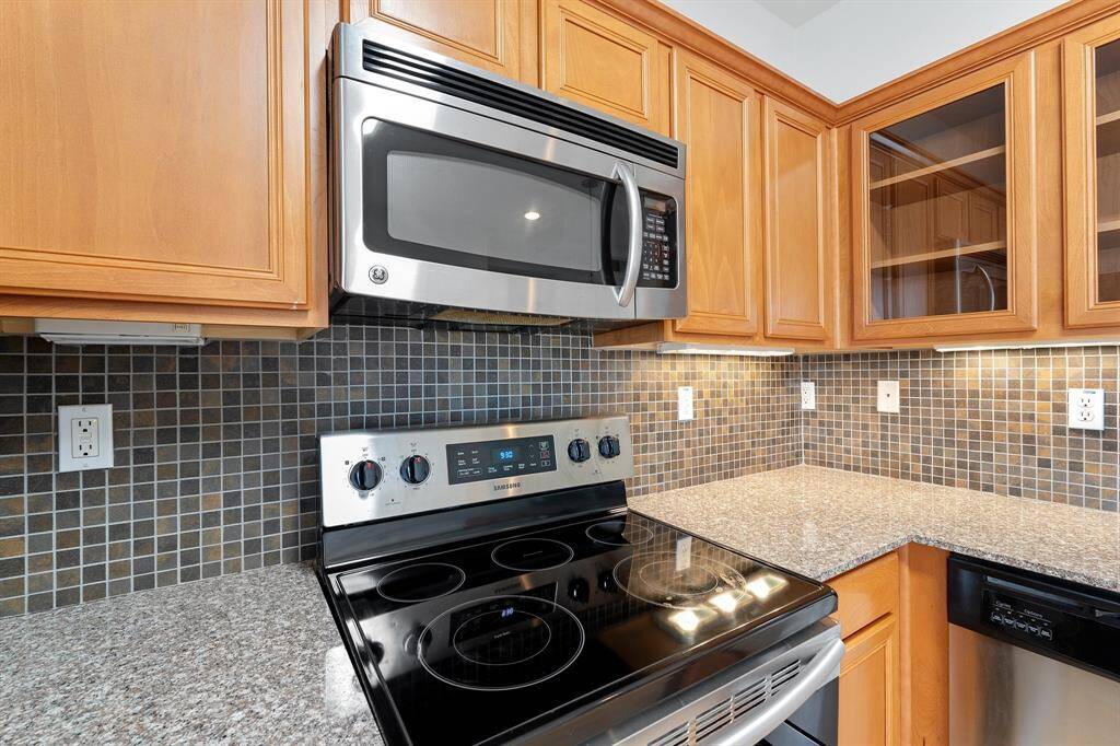 The kitchen features wood cabinets, tile backsplash, and stainless steel appliances.