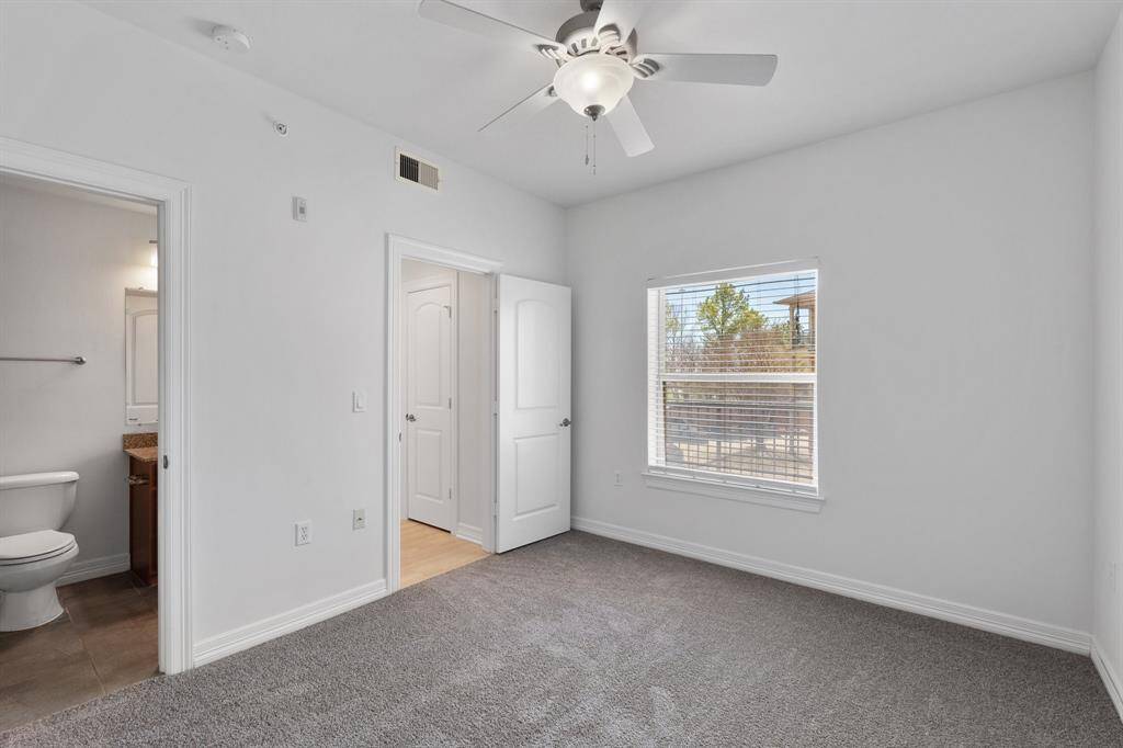 Secondary bedroom features plush carpet and a ceiling fan.