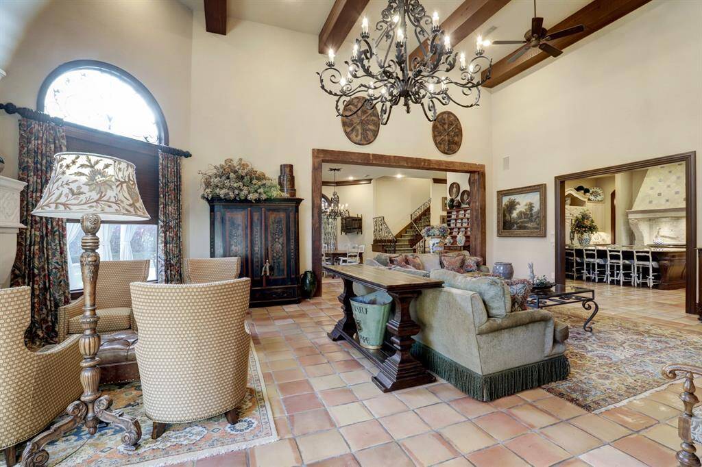 Large family room with reclaimed wood beams, high ceilings, continued terra cotta tile floors, grand stone fireplace and livable flow from kitchen to breakfast rooms.