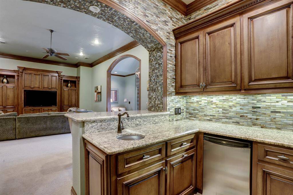 Perfect for entertaining, the upstairs living area features a convenient kitchenette with granite countertops, sink, and dishwasher, complemented by a spacious open-concept design ideal for hosting gatherings.