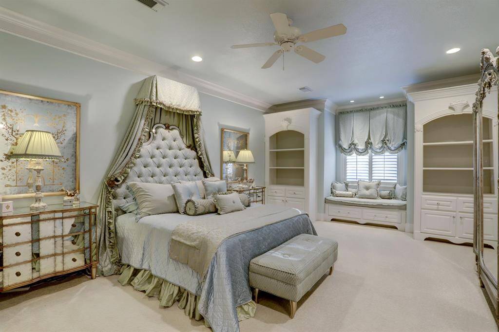 Another upstairs bedroom offers a generous retreat, showcasing custom detailed built-ins and window seating, along with an en-suite bath for enhanced convenience and a walk-in closet for ample storage.