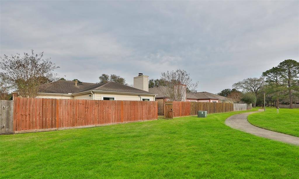View of the back fence and gate from the greenbelt which has sidewalks all around the neighborhood. Perfect for walks.