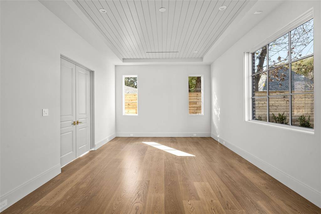 A unique feature, this thoughtfully designed downstairs room offers exceptional flexibility, making it ideal as a game room, media room, or a second primary bedroom. Its spacious layout provides ample room for entertainment setups, whether its a large sectional for movie nights or game tables for gatherings. Expansive windows bring in natural light, while the custom paneled ceiling adds architectural charm. The white oak hardwood floors enhance the warmth of the space.