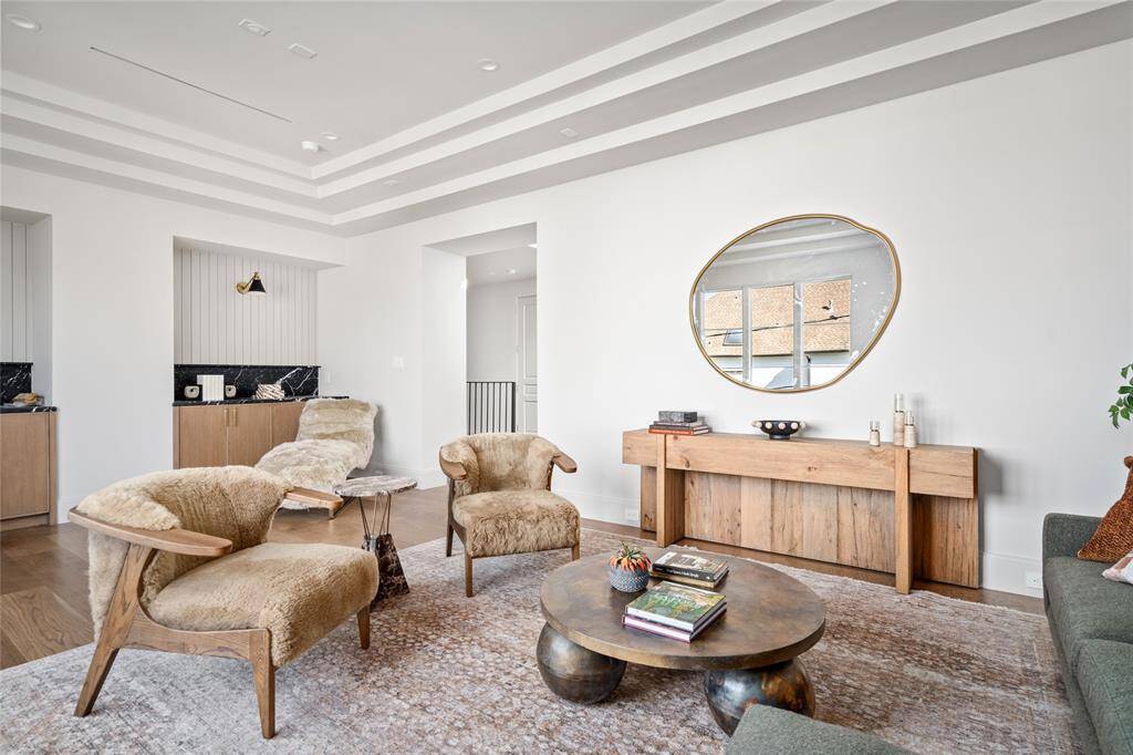 The inviting den features a stylish wet bar with sleek marble counters and an under-counter beverage center. Aerin sconces provide elegant illumination, while custom built-in cabinetry and shelving offer ample storage, complemented by two-tone brass cabinet pulls for a refined touch.
