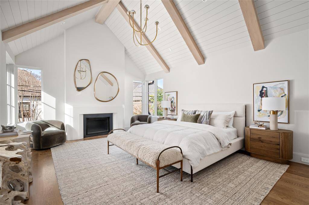A haven of refined elegance, the primary bedroom is designed to impress with its soaring ceilings and thoughtful architectural details. Overhead, a striking Kelly Wearstler chandelier adds a sculptural focal point, beautifully complementing the stained wood beams and painted tongue-and-groove ceiling. Expansive windows fill the space with natural light, while white oak hardwood floors lend warmth and timeless sophistication to this luxurious retreat.