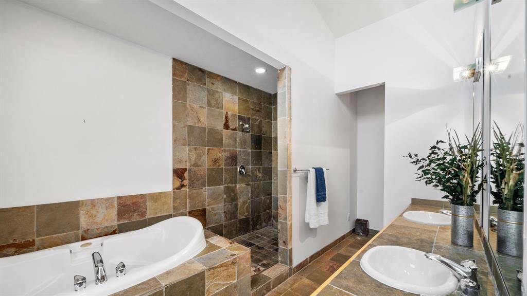 Primary bathroom has double sinks, whirlpool tub, and glass free oversized walk-in shower with dual shower heads.