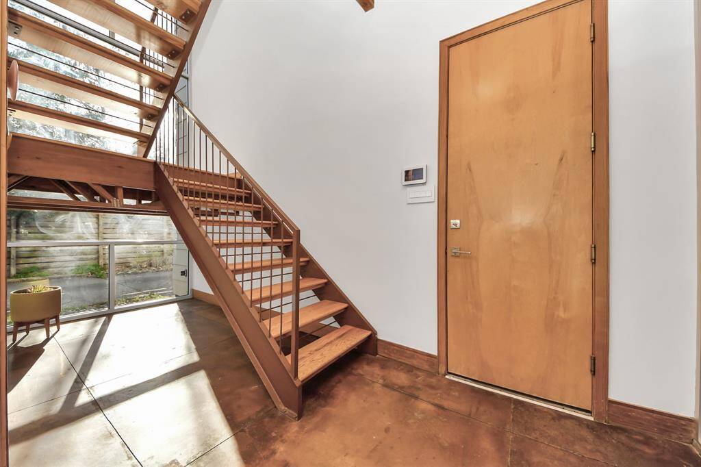 Floor to ceiling windows in stairwell located in the center of the home provides wonderful natural light. The open-riser steel staircase looks over the driveway and courtyard.  This is the entry from the 2 car garage as well.