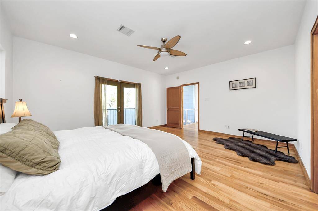 view of Juliet balcony in spacious secondary bedroom with hardwood floors and en-suite full bathroom