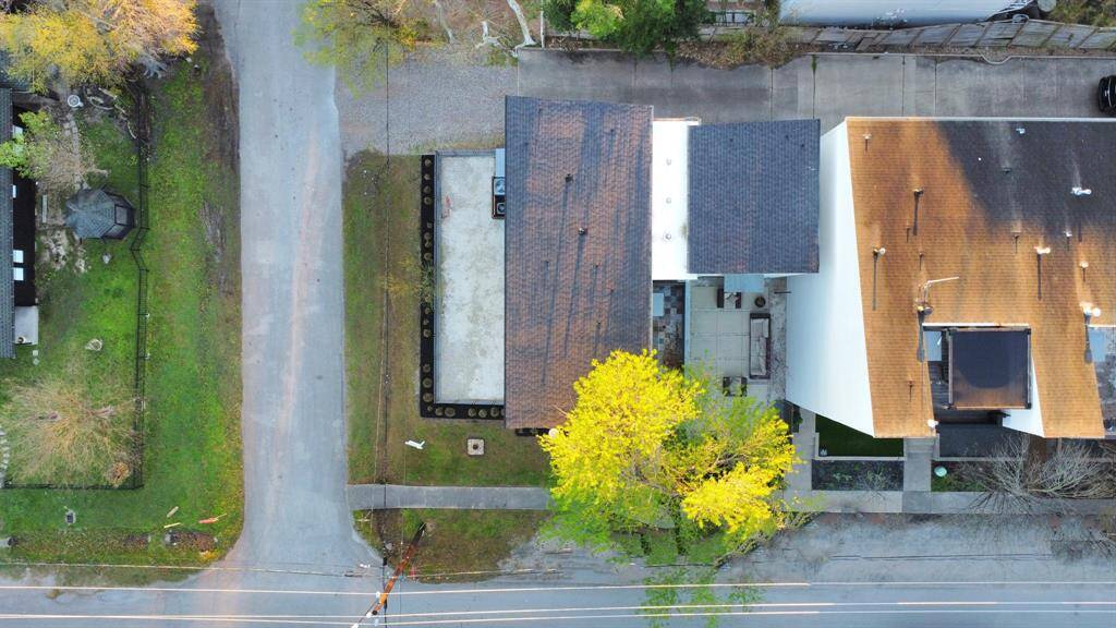 Aerial view showing home on large corner lot with lush tree,  fully fenced side yard and courtyard, NEW roof, and paved driveway, and plenty of parking options