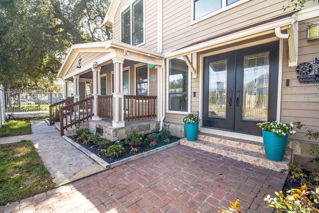 Charming home with a welcoming front porch, double glass doors, and well-maintained landscaping. The entrance features a paved walkway, decorative planters, and a cozy seating area, enhancing curb appeal.