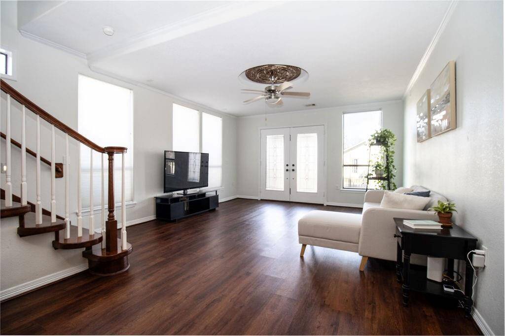 Bright and spacious living room with large windows for natural light, and French doors leading outside.