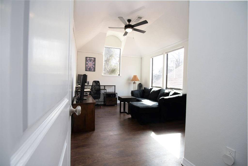 Third bedroom upstairs features a cozy setup with a vaulted ceiling, large windows for natural light, a ceiling fan, and luxury vinyl plank floors.  and a modern, airy feel, ideal for a home office or relaxation space.