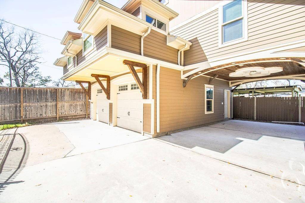 This photo showcases a spacious, well-maintained driveway with a two-car garage and a covered carport area. The exterior features a modern design with neutral-toned siding, complemented by a wooden fence for privacy. Perfect for multiple vehicles or outdoor activities.