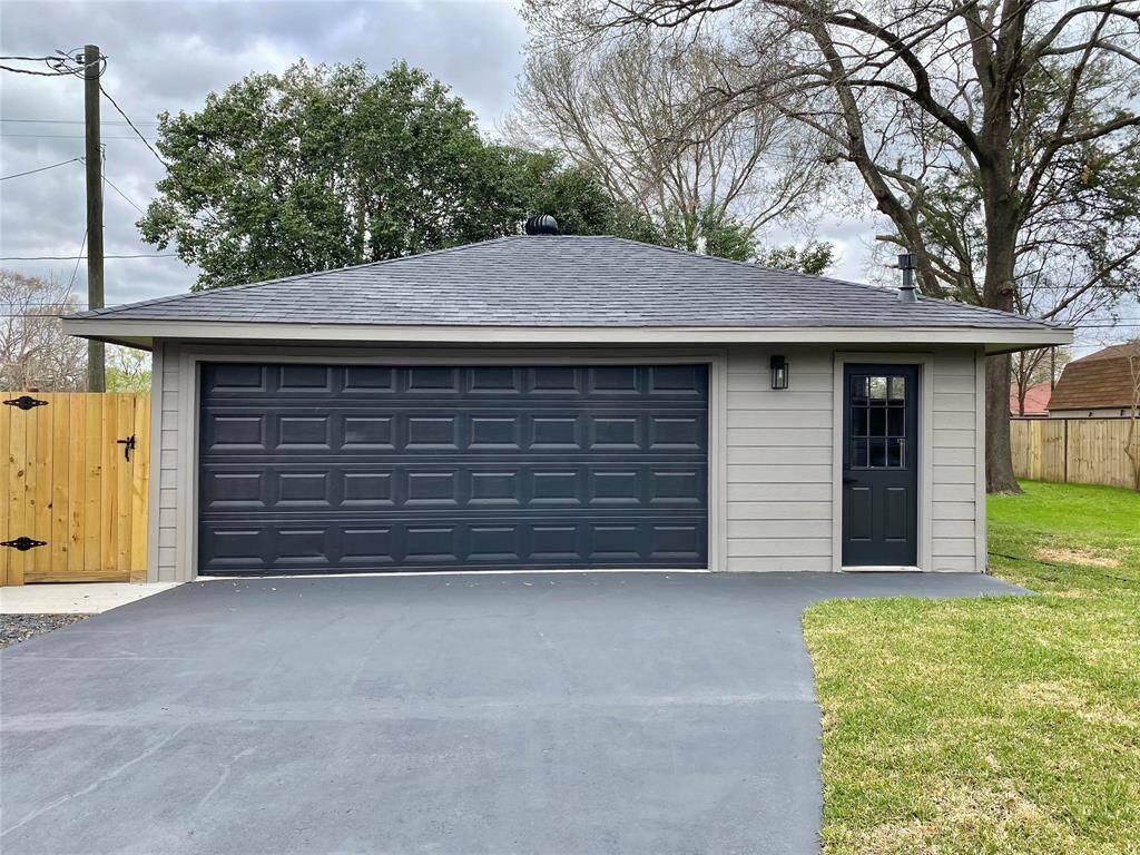 2 car over-sized detached garage  located in the back of the house has a  modern sleek look with an additional side entrance. It features a paved driveway and an additional fenced in area for trash and recycling bins.