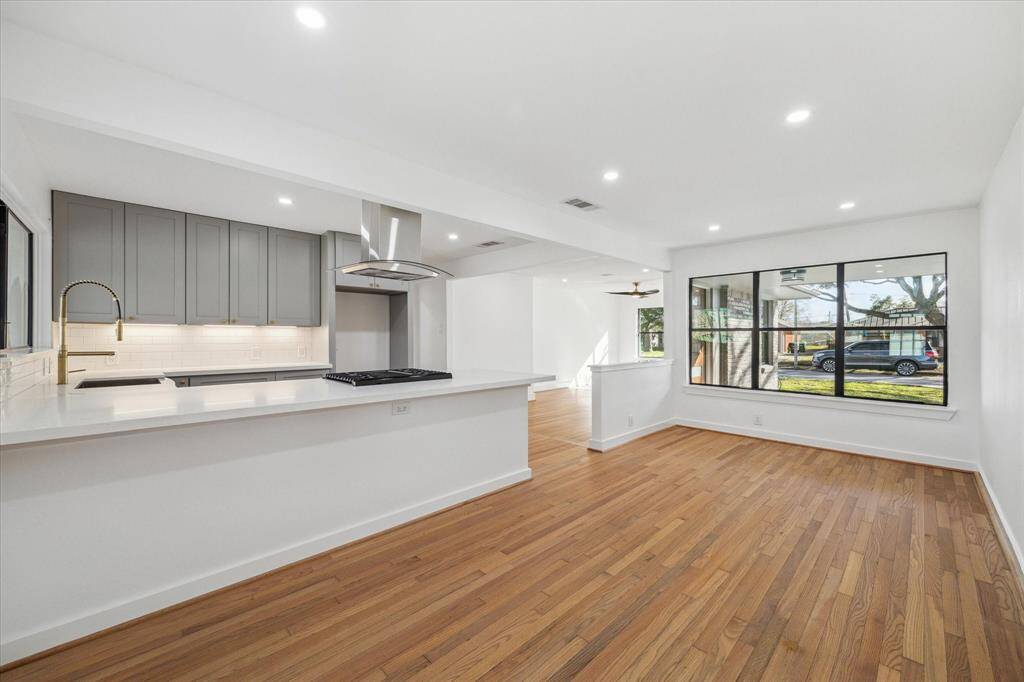 Bright and open breakfast space with hardwood floors and recessed lighting. The kitchen features modern cabinetry, a central bar and large windows for ample natural light. This layout allows for ample space throughout.