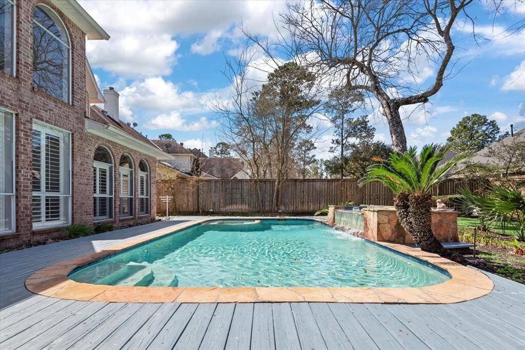 This spacious backyard features offering a blend of elegance and comfort for outdoor entertainment. large in-ground swimming pool with an attached spa, and a surrounding wooden deck.