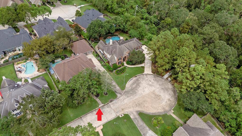 This aerial image showcases the spacious driveway, mature trees and adjacent greenbelt access, offering privacy and a sense of seclusion.