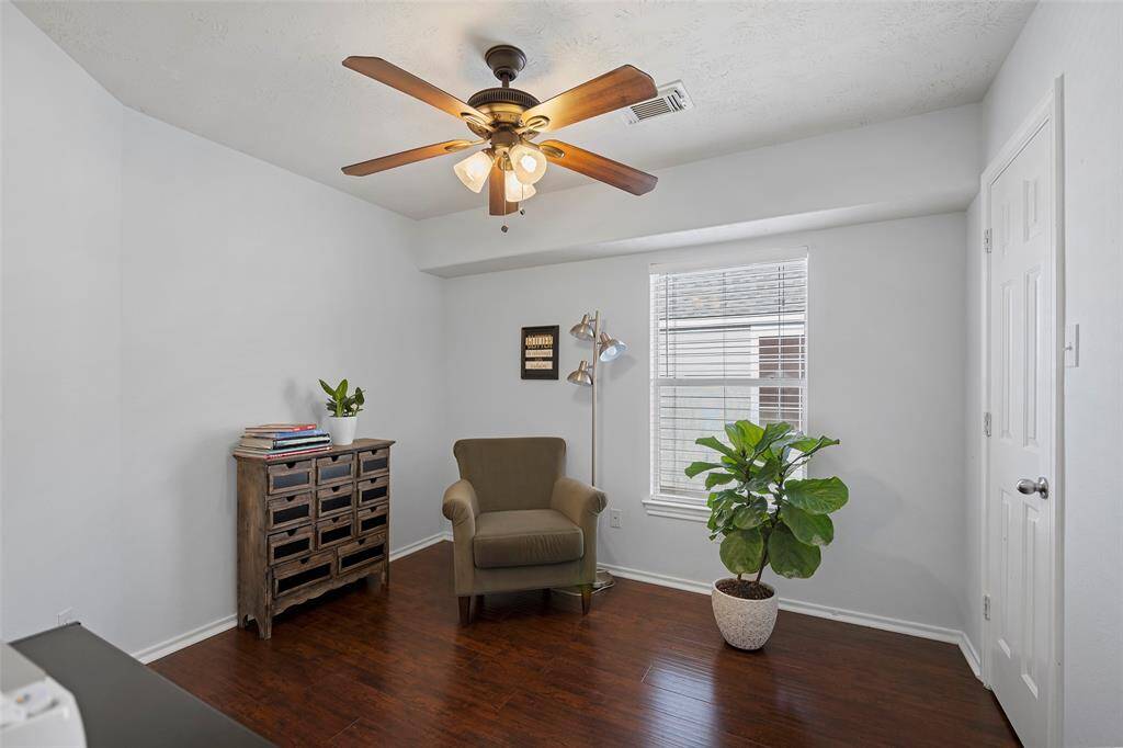 Second bedroom with a ceiling fan, hardwood floors, and a window providing natural light.
